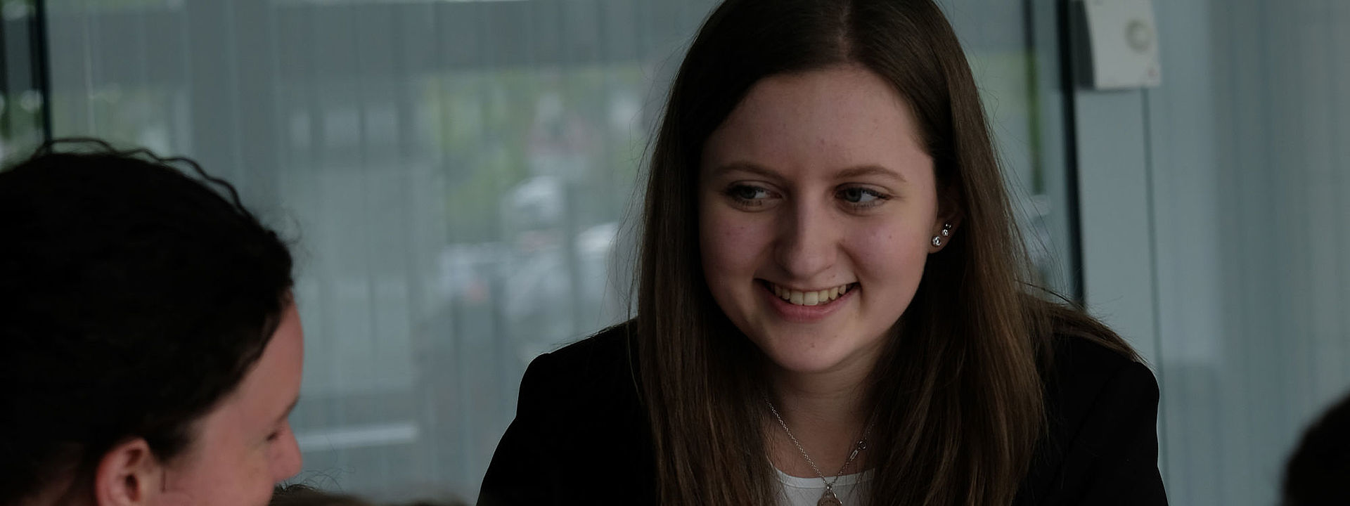 Mehrere Personen hören einer Frau vor einem Fenster zu