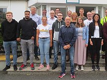 Ausbildungsstartgruppenfoto Arnsberg Man sieht etwa 20 Personen, welche vor einem Gebäude in mehreren Reihen für ein Gruppenfoto posieren.