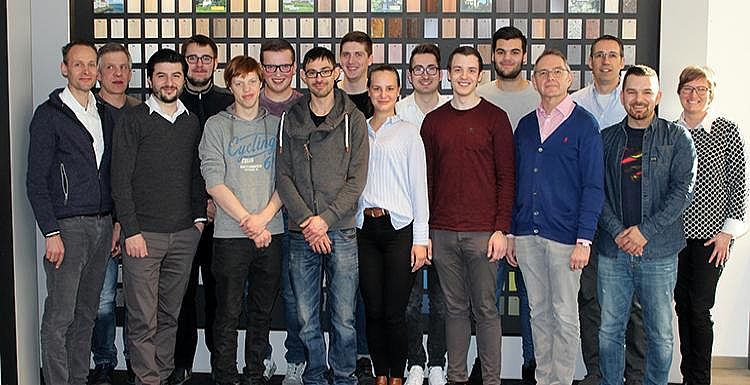 Man sieht etwa 15 Auszubildende und Ausbilder, welche in zwei Reihen für ein Gruppenbild posieren.