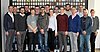 Man sieht etwa 15 Auszubildende und Ausbilder, welche in zwei Reihen für ein Gruppenbild posieren.