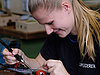 A woman carefully working on a small circuit board