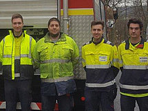 Auszubildende vor Feuerwehrfahrzeug Zu sehen sind 5 Auszubildende in Feuerwehrschutzkleidung vor einem Feuerwehrauto