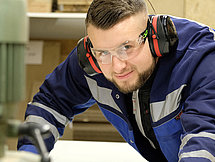 Ein Mann in Schutzkleidung bedient große Maschinen