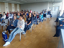 Neumarkter Ausbildungsforum Man sieht etwa 30 Personen von vorne, welch in Stuhlreihen sitzen und einer Person zuhören, welche nicht im Bild zu sehen ist.