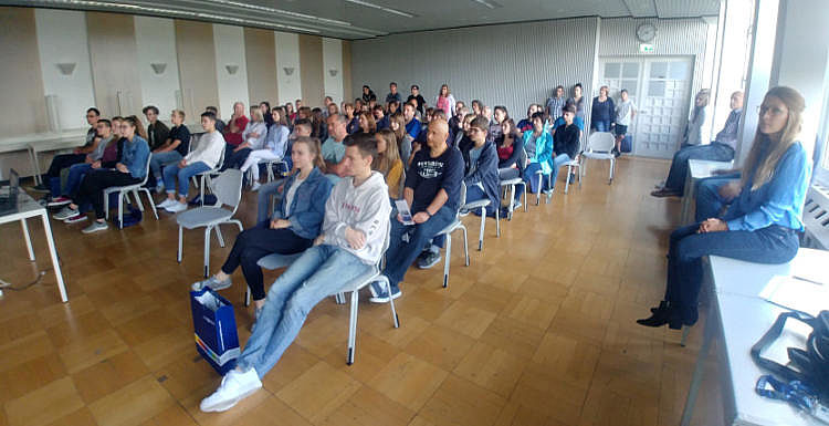 Neumarkter Ausbildungsforum Man sieht etwa 30 Personen von vorne, welch in Stuhlreihen sitzen und einer Person zuhören, welche nicht im Bild zu sehen ist.