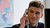 A young man answering the phone at his desk