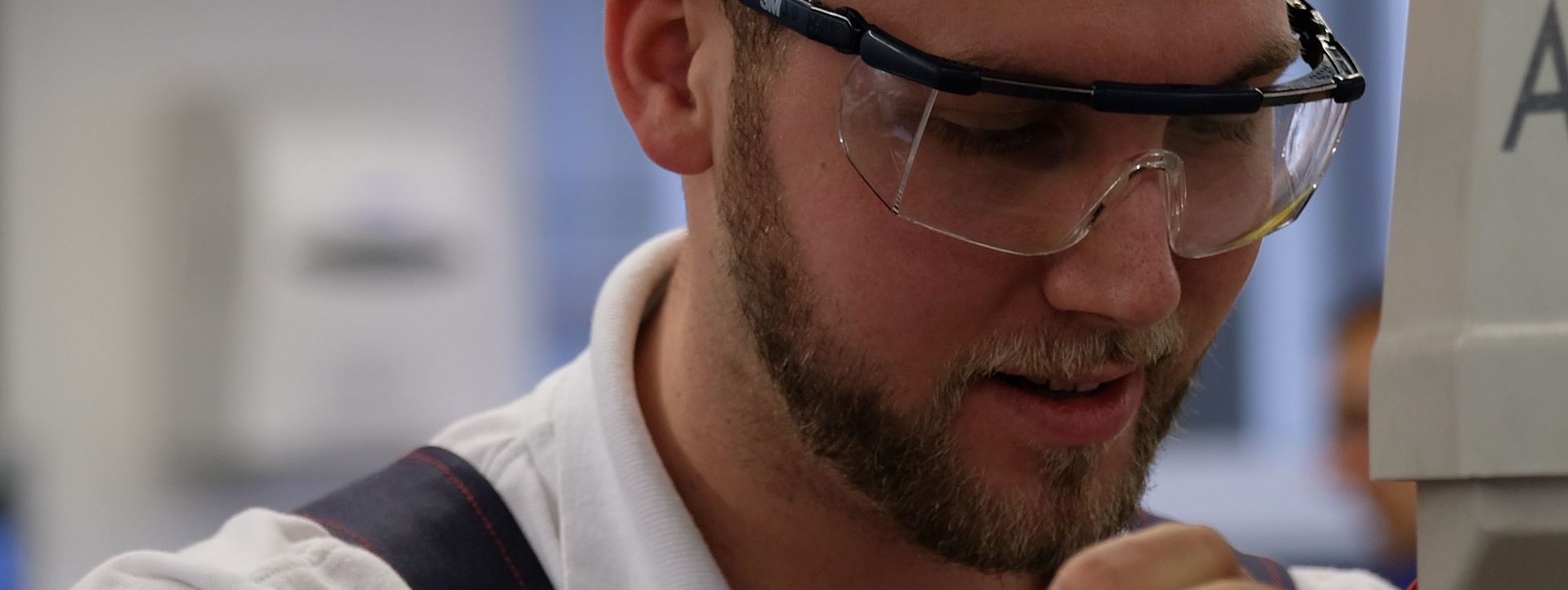 Ein Mann in Schutzkleidung bedient eine kleine Maschine