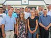 Man sieht etwa 20 Auszubildende und Ausbildende, welche in vier Reihen für ein Gruppenbild posieren