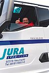 Foto eines Fahrers im Führerhaus eines JURA-Transporters, der den Daumen nach oben zeigt
