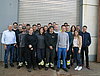 Etwa 20 Auszubildende und Ausbilder posieren vor einem Lagertor für ein Gruppenfoto.