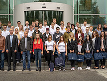 Gruppenfoto Ausbildungsjahrgang 2018 Man sieht etwa 30 Personen, welche vor einem Gebäude in mehreren Reihen für ein Gruppenfoto posieren.