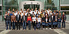 Man sieht etwa 30 Personen, welche vor einem Gebäude in mehreren Reihen für ein Gruppenfoto posieren.