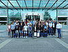 Etwa 30 Auszubildende und Ausbilder posieren vor einem gläsernen Gebäude für ein Gruppenfoto