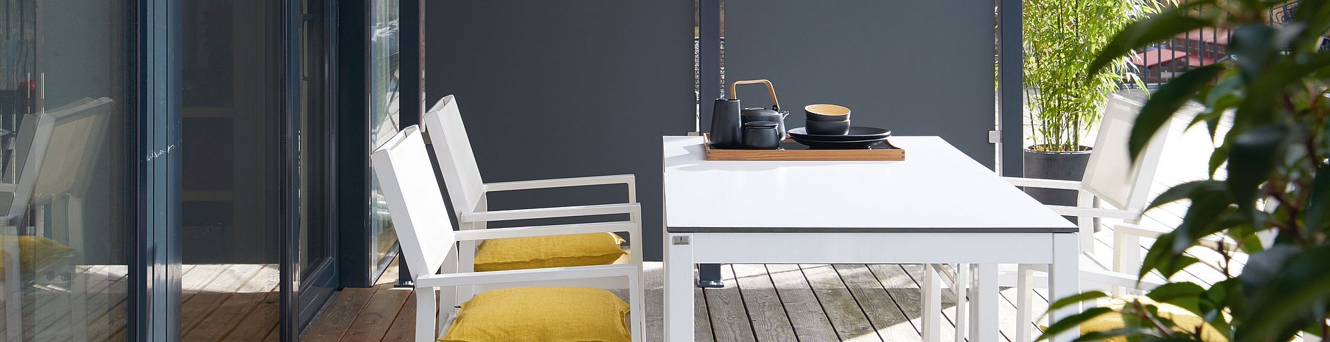 A sunny terrace with outdoor furniture and a partition wall made of Compact XTerior.