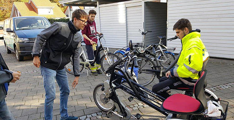 Auszubildende an Fahrrädern Zu sehen sind 4 Auszubildende, welche zwischen Garagen an Fahrrädern basteln