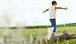 A boy balancing on a tree trunk on a green meadow