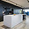 An open-plan kitchen-living room with a black back wall. View of the white kitchen unit with tap, breakfast bar and bar chairs