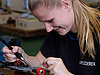 The picture shows a woman carefully working on a circuit board