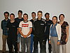 Gruppenfoto der Absolventen und ihrer Ausbilder vor einer weißen Wand