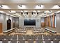 The photo shows the great hall of the new town hall. It features a big screen, light materials and some wooden elements.