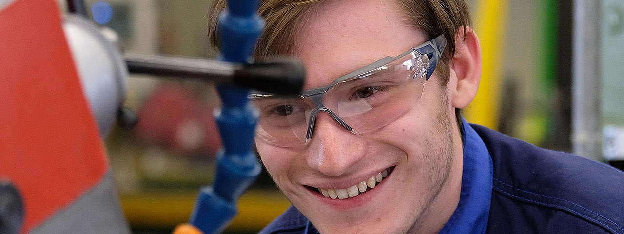 Symbolbild Holzbearbeitungsmechaniker Ein junger Mann in Schutzkleidung bedient eine Maschine zur Holzbearbeitung