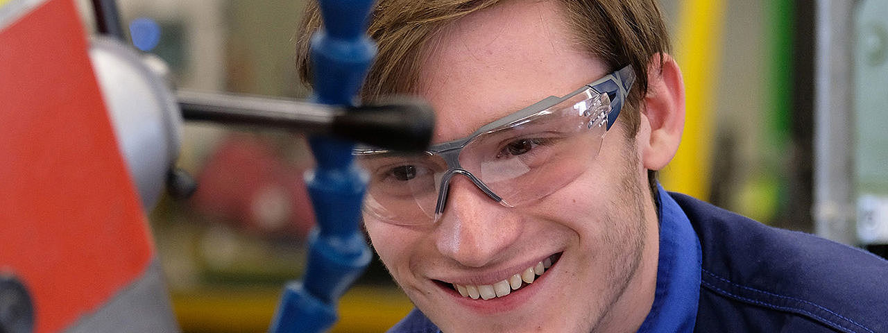 Symbolbild Holzbearbeitungsmechaniker Ein junger Mann in Schutzkleidung bedient eine Maschine zur Holzbearbeitung