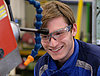 A young man in protective gear operating a machine processing wood