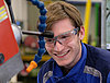 A young man in protective gear operating a machine processing wood