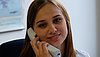 A young woman answering the phone at her desk