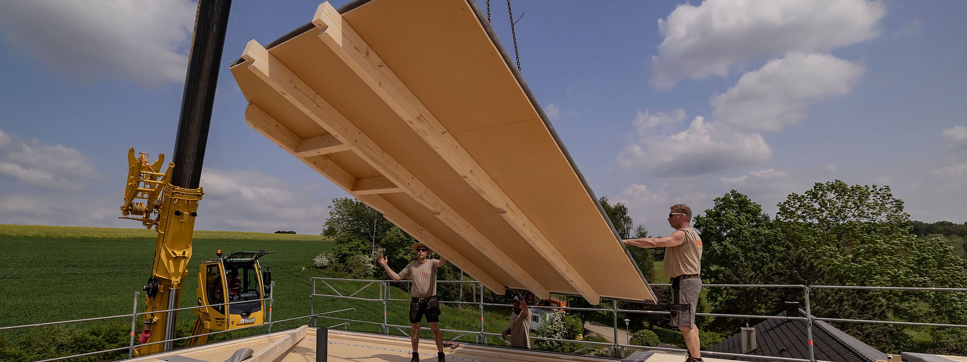 Wall in panelled construction hanging from a crane