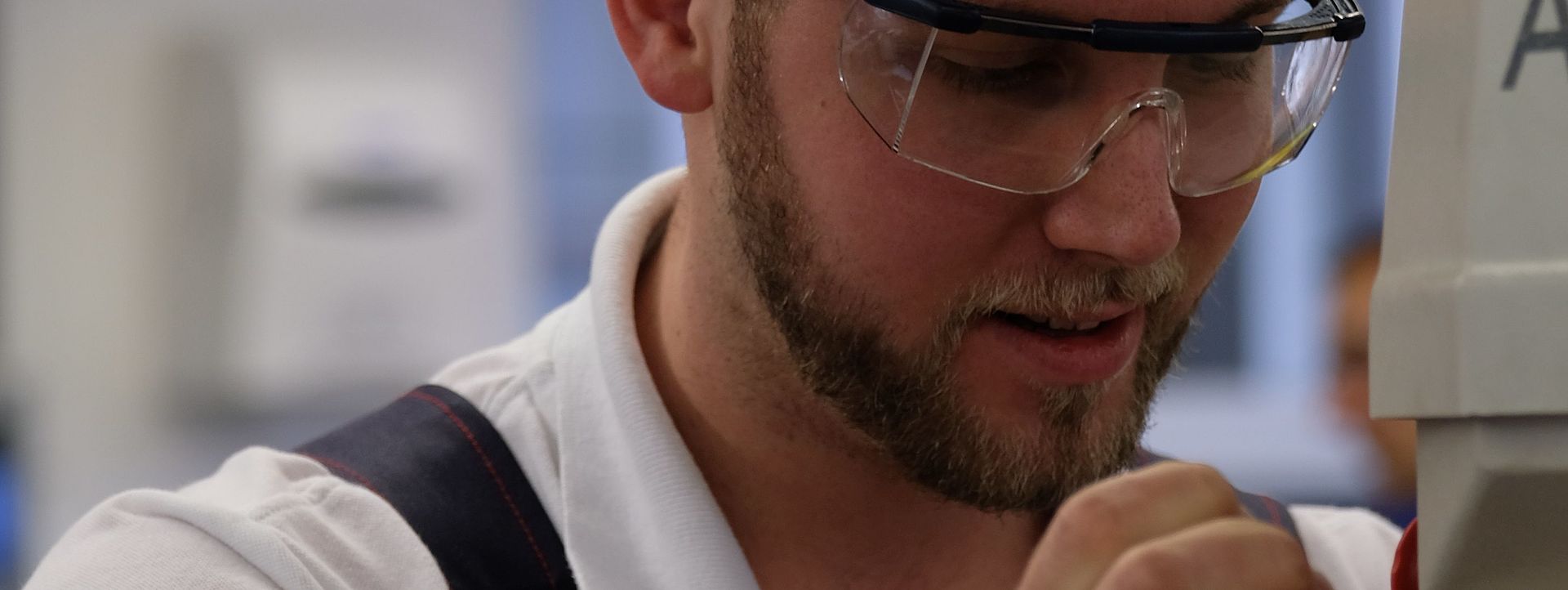 Ein junger Mann in Schutzkleidung bedient eine kleine Maschine