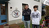 Zwei junge Männer posieren für ein Foto vor einer Kindertagesstätte