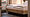 Frisch gemachtes Hotelbett mit weißen Bezügen in natürlichem Ambiente von Holzoberflächen und hellen Cremetönen