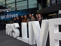Gruppenbild Fachmesse Nürnberg Man sieht 8 Auszubildende hinter einem physisch aufgestellten Schriftzug. Die Buchstaben sind etwa 1,50m groß.