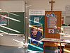 Man sieht einen Austellbanner von Pfleiderer in einem Klassenzimmer. Der Banner zeigt einen Auszubildenden und einen QR-Code.