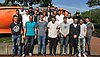 Etwa zwanzig Auszubildende posieren in 3 Reihen für ein Gruppenbild. Es ist sehr sonnig.