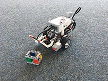 Lego Mindstorms Roboter Man sieht einen Lego Mindstorms Roboter auf einem grauen Teppichboden