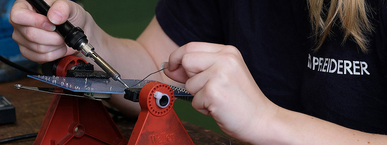 Symbolbild Elektroniker Eine junge Frau arbeitet sorgfältig an einer Leiterplatte