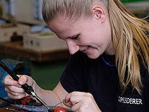Representative image Electrician A young woman carefully working on a circuit board