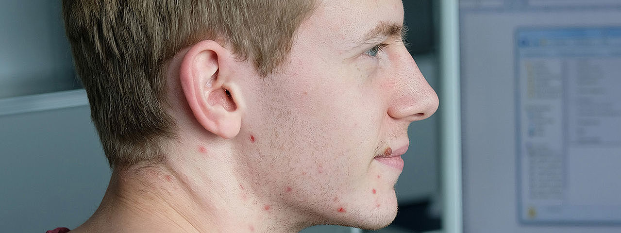 Symbolbild Informatikkaufmann A man in a red sweater sits in front of his PC