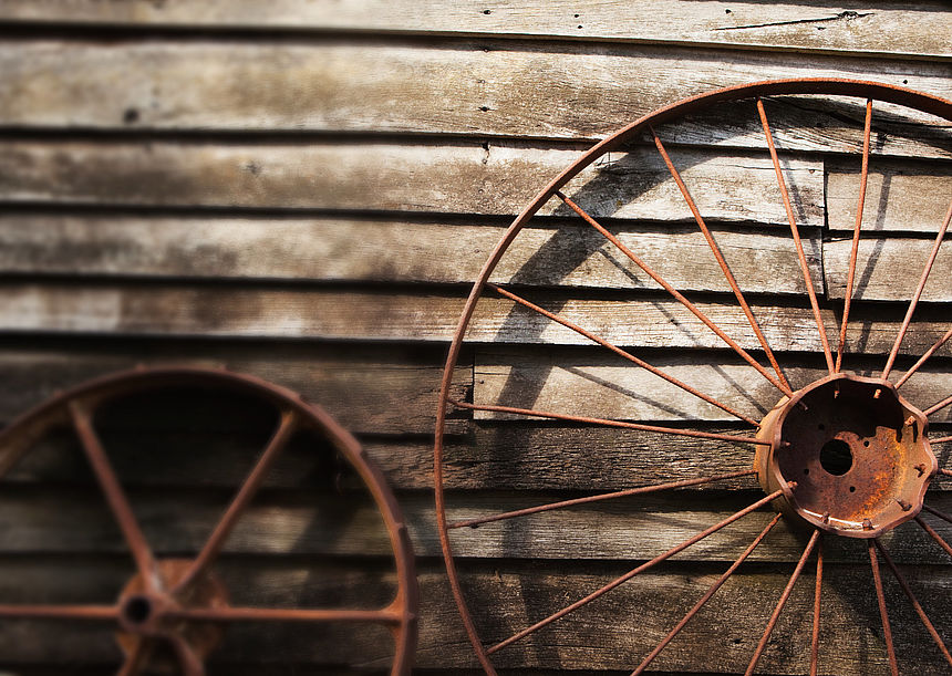 As time goes by An old wagon wheel in front of a wall of old, weathered wooden boards.