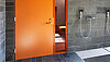 Orangefarbene Tür neben einer begehbaren Dusche in einem Sauna-Bereich oder einem Spa