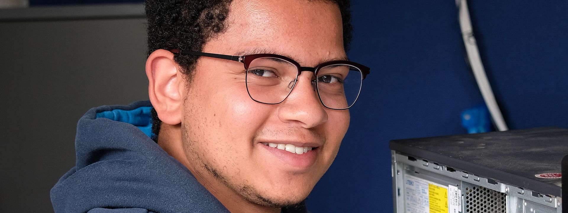 Symbolbild Informatiker Das Bild zeigt einen jungen Mann, welcher einen Computer repariert