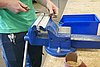 Eine Person schleift ein Herz aus Metall mit einer Pfeile an einer Werkbank