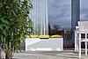 Eine weiße Bank auf einer Terrasse mit gelben Kissen, hergestellt aus XTerior compact.