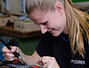 A young woman carefully working on a small circuit board