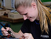 A young woman carefully working on a small circuit board