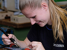  Eine junge Frau arbeitet sorgfältig an einer kleinen Platine