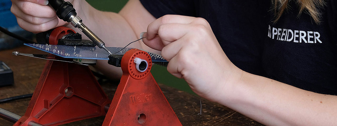 Symbolbild Elektroniker  Eine junge Frau arbeitet sorgfältig an einer kleinen Platine