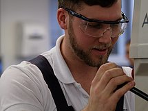 Das Bild zeigt einen Mann in Schutzkleidung bei der Handhabung einer Maschine